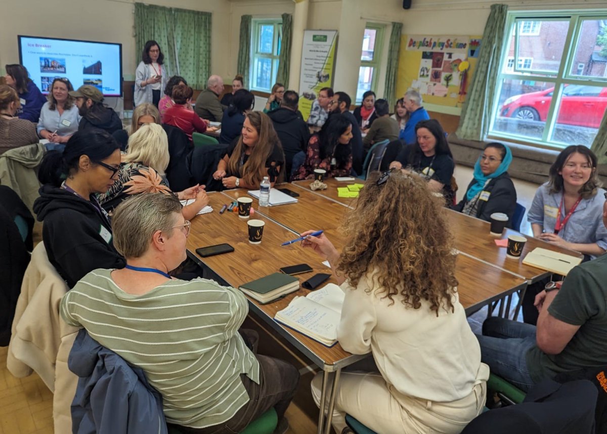 community group meeting of people chatting around multiple tables