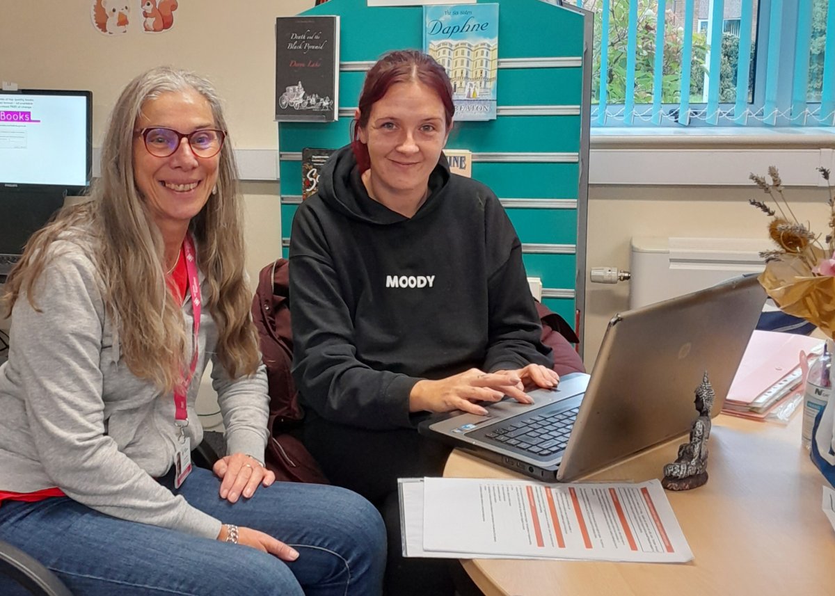 two women smiling at desk with laptop