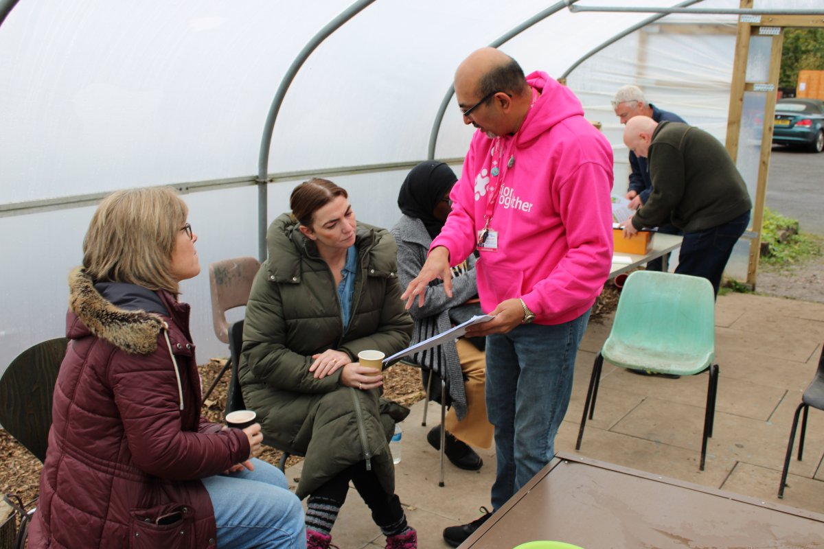 Community Development Worker in pink jumper talking to members