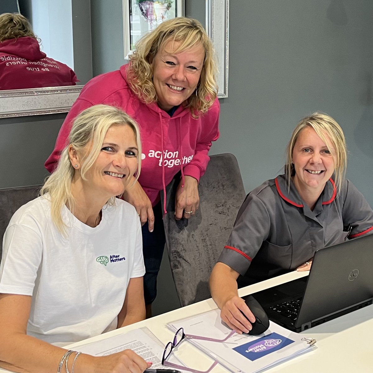 three women at group meeting around desk smiling