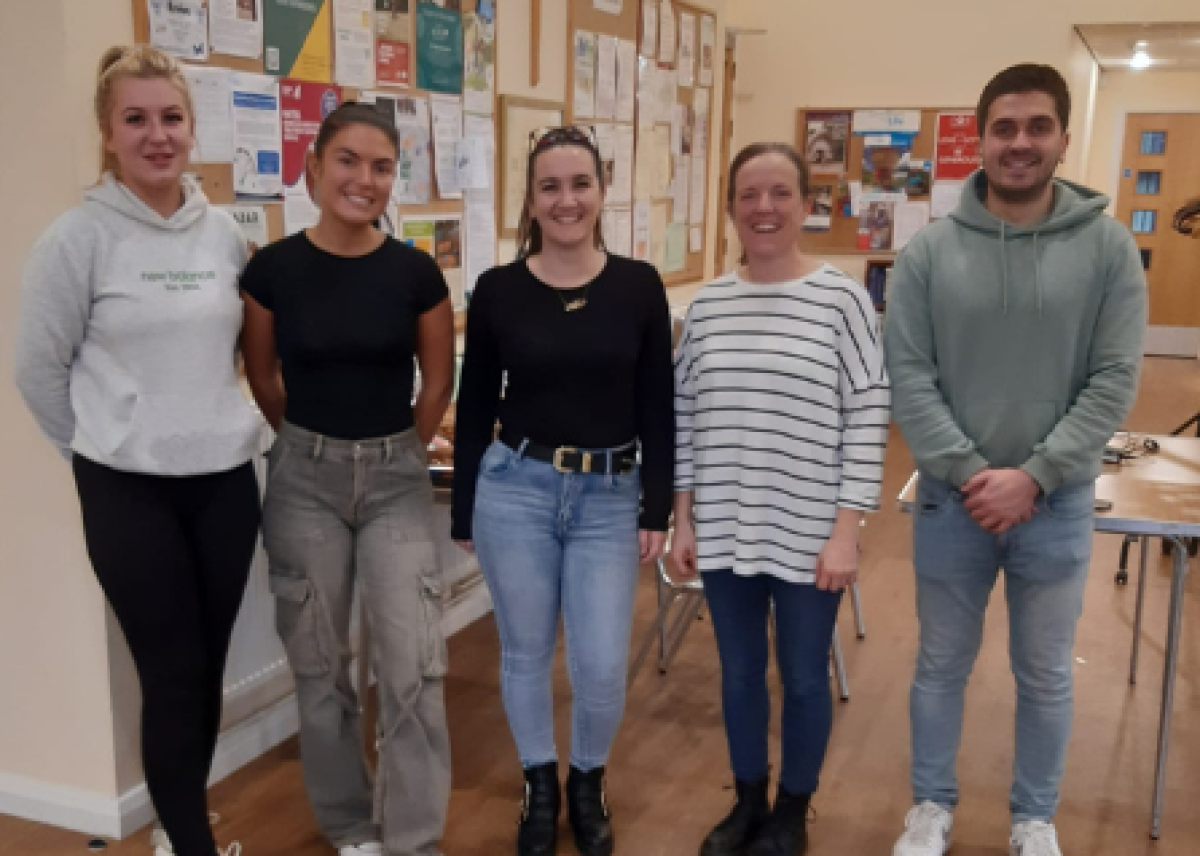 group of five young people in community centre smiling