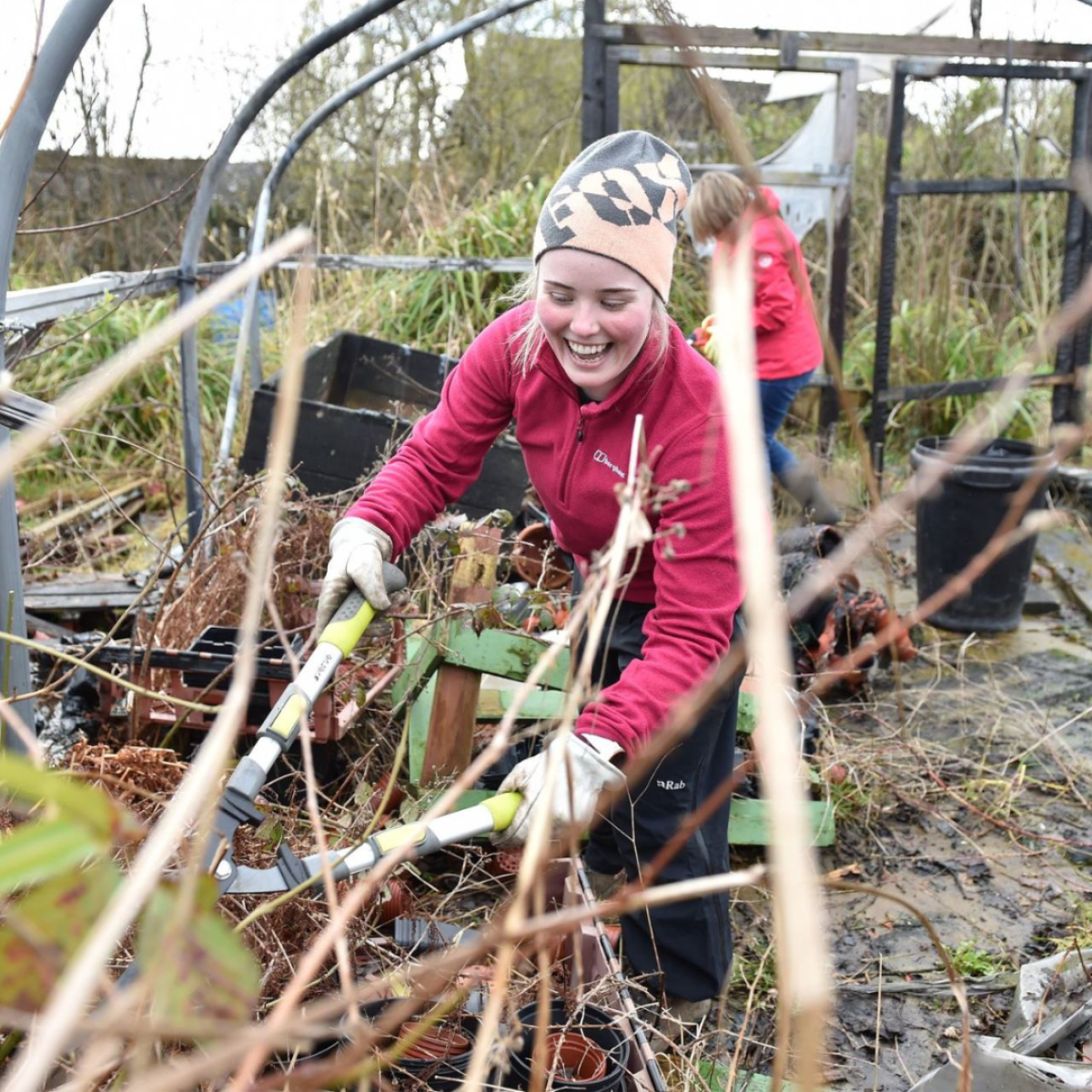 woman smiling using garden shears to clear dead wood