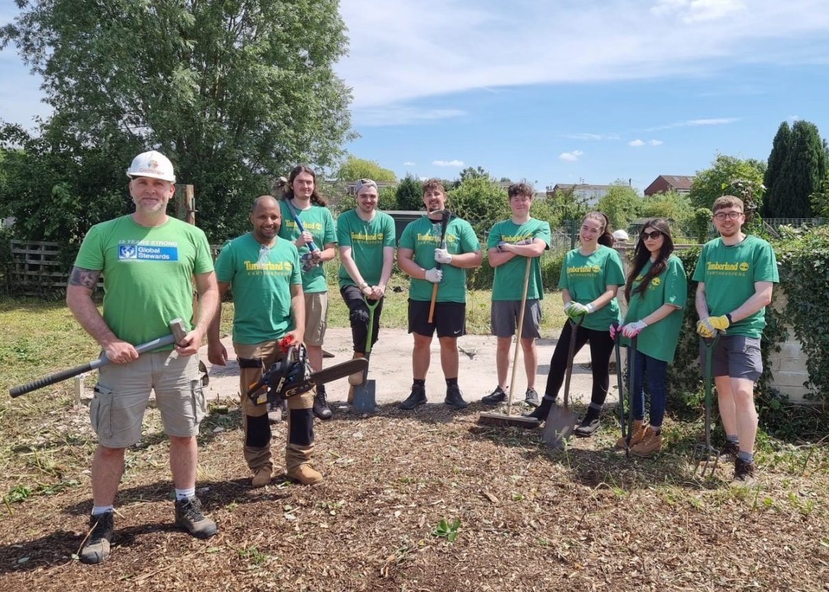 group of people stood holding gardening tools