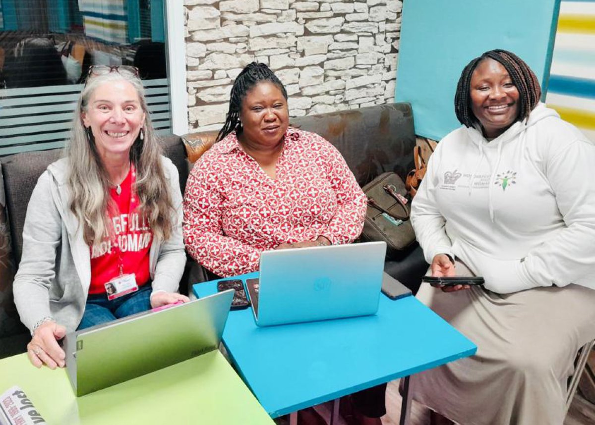 three women smiling at meeting with laptops