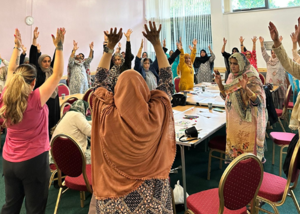 community group of women with arms in the air and backs to the camera