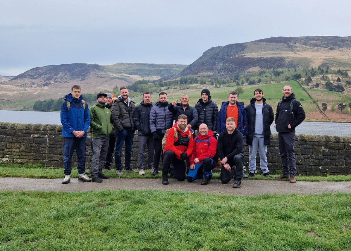 group of men in outdoor hiking clothing in front of lake and mountain background