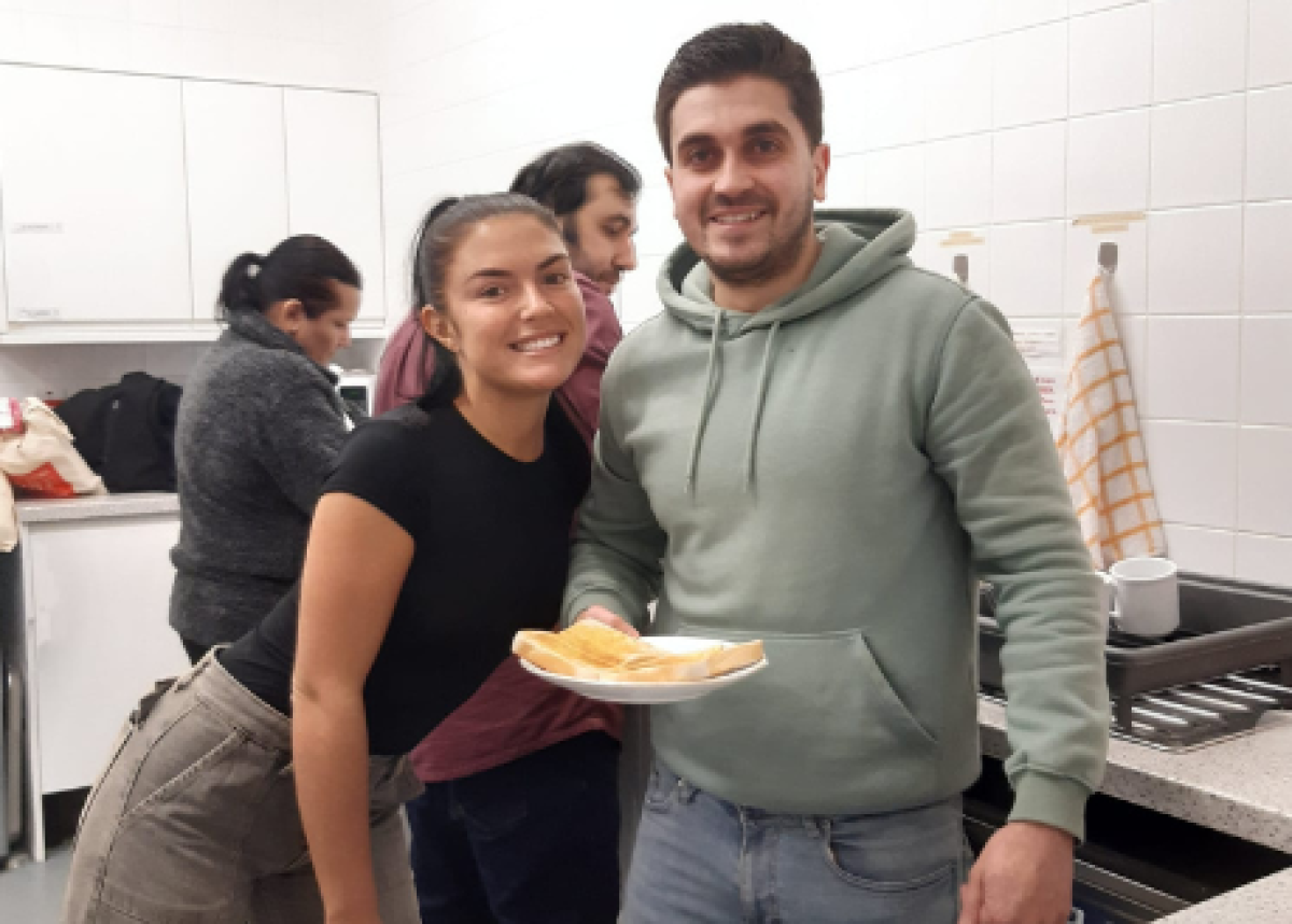 young woman and man smiling helping in community kitchen