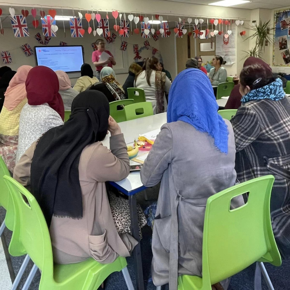 community group meeting with woman presenting and speaking at front of room