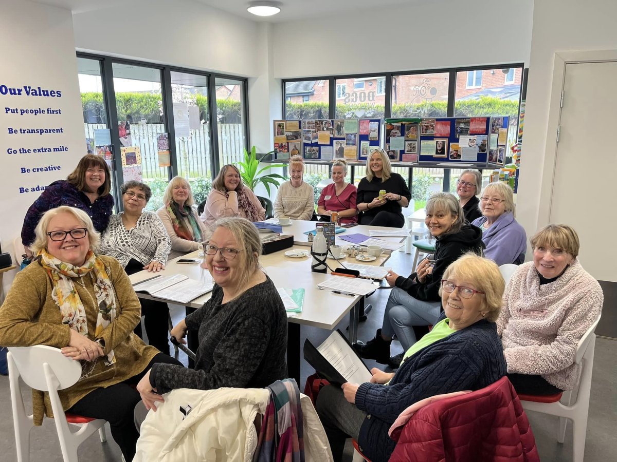 community group meeting of people gathered around table smiling