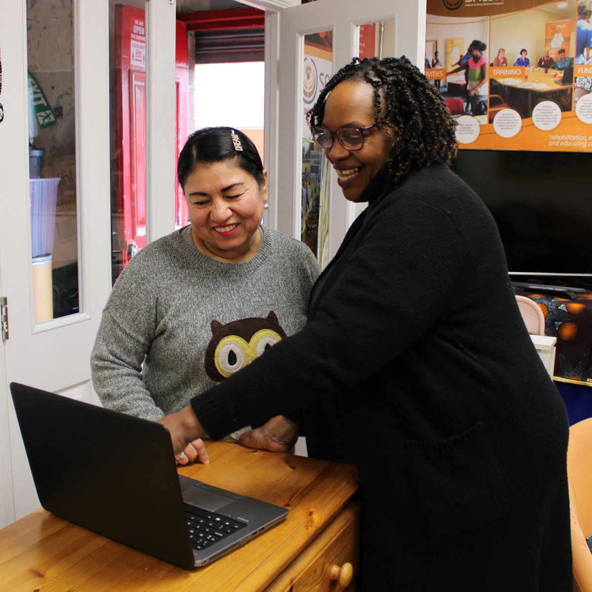 two women looking at laptop and smiling