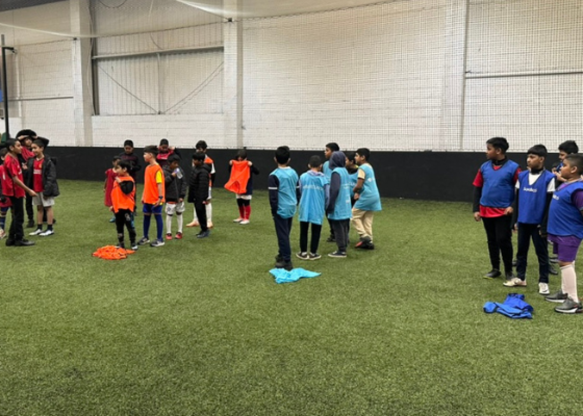 teams of children in coloured bibs lining up to play games on indoor football pitch