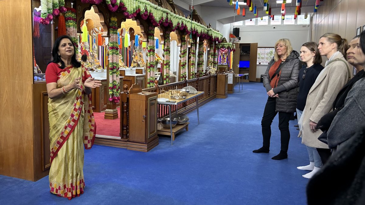 lady in sari talking to group of people in hindu temple