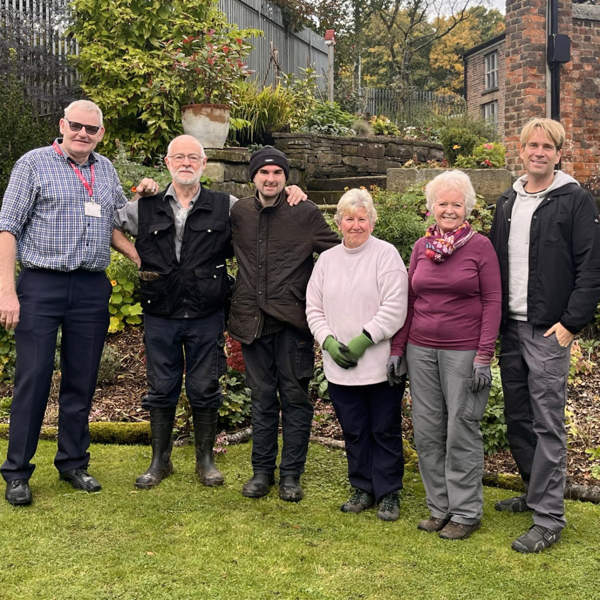 group of people stood on lawn in front of old hall building