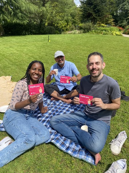 Group of sat on a blanket holding up Thank You postcards