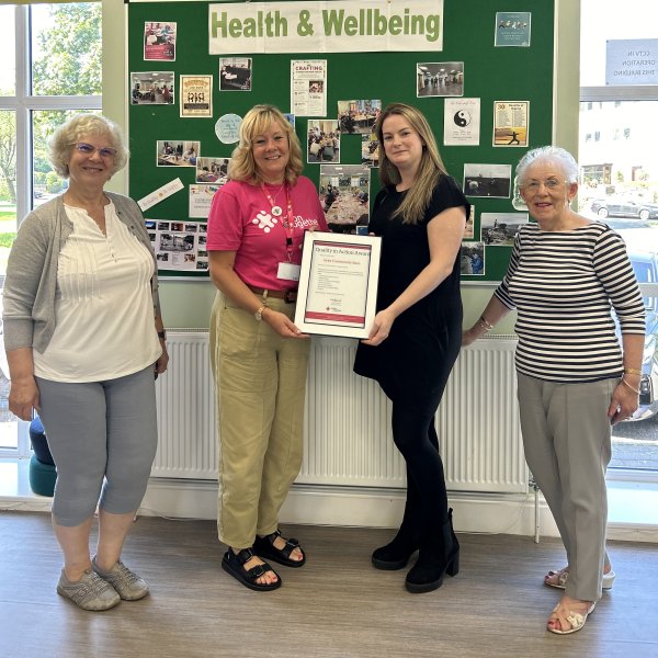 group of women smiling being presented with a quality award certificate