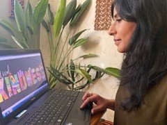 Artist Bushra Sultana looking at the Radical Kindness design on her laptop